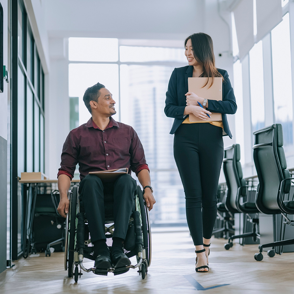a woman talking to a guy in a wheelchair at a workplace