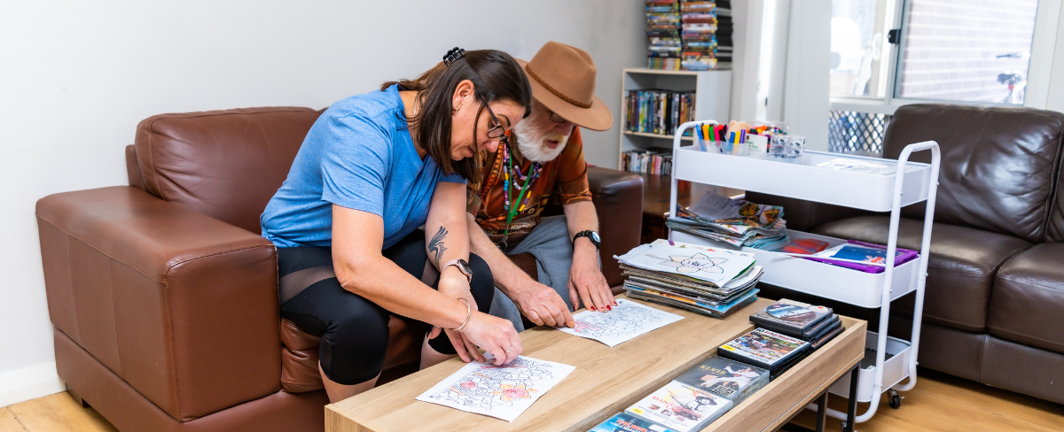 Image of a female support worker doing craft with an NDIS participant