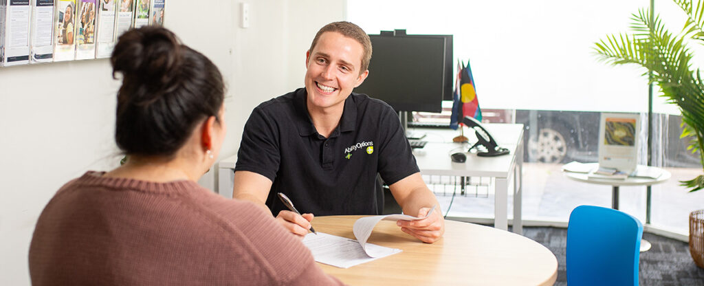 Ability Options Support Coordinator smiling at participant in office setting